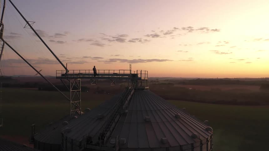 Man walks across a gangway to the top of a silo
