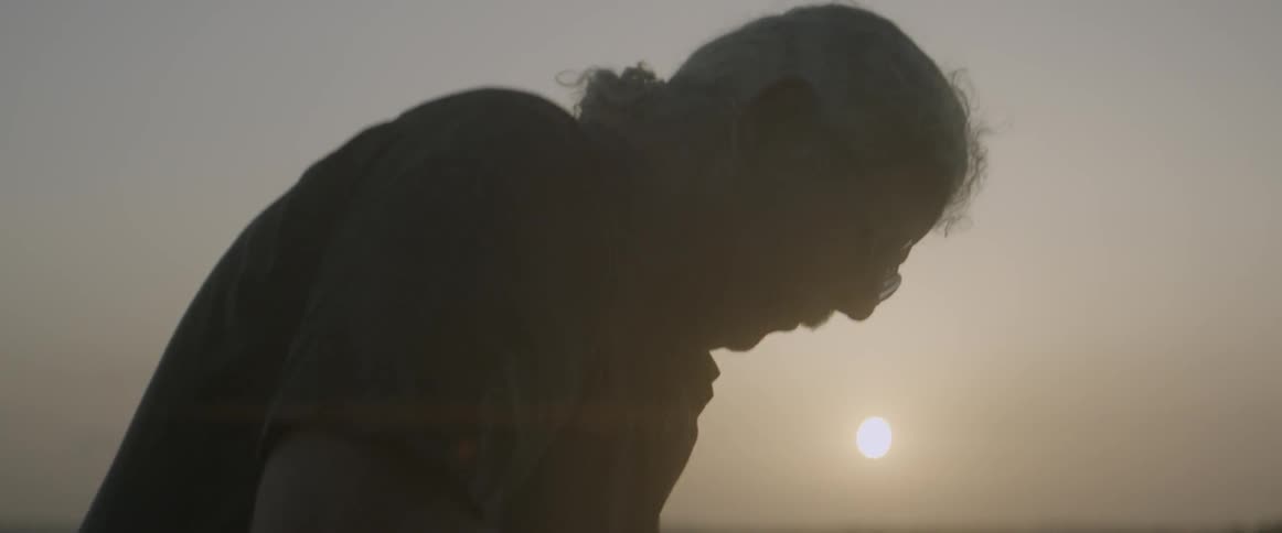 A man is leaning forward at sunset