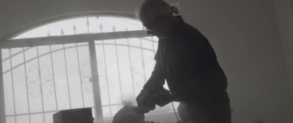 A man works with a grinder on a sculpture