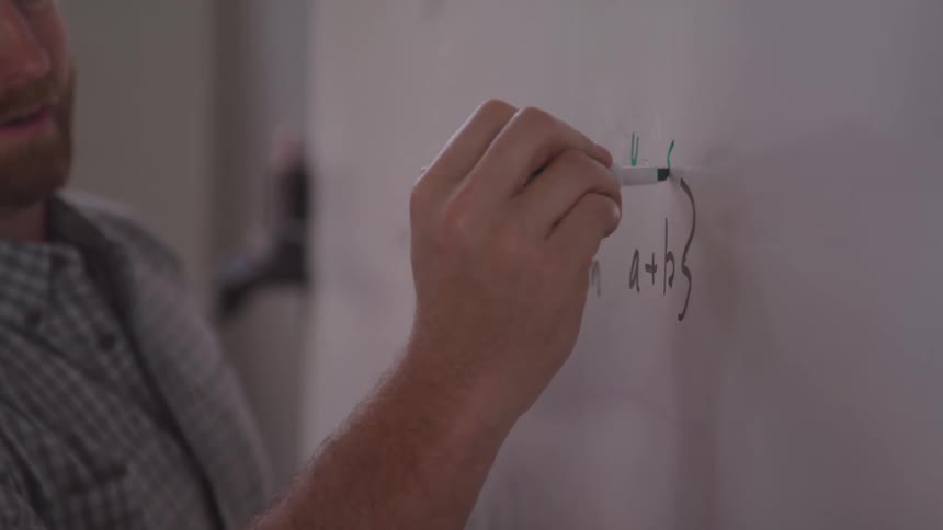 The teacher is teaching a moth class while using a white board