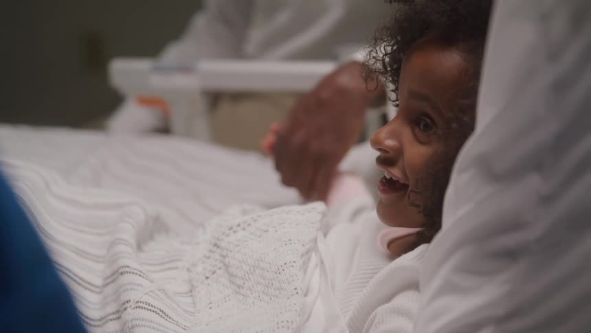 The child in the hospital bed is smiling