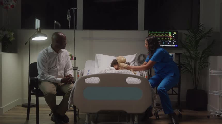 A father and nurse sit beside a childs hospital bed offering comfort and care holding a teddy bear