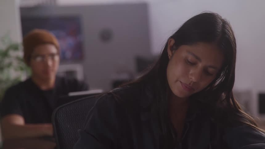 Woman indoors with a man sitting in the background