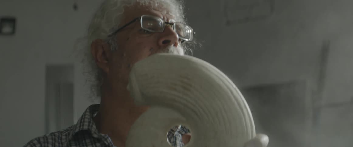 A man blows dust off a sculpture