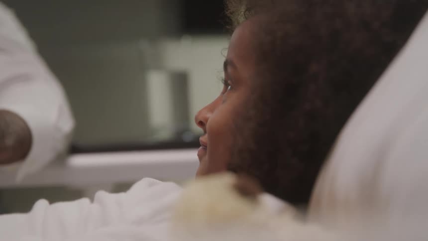 The child is looking at a visitor in the hospital