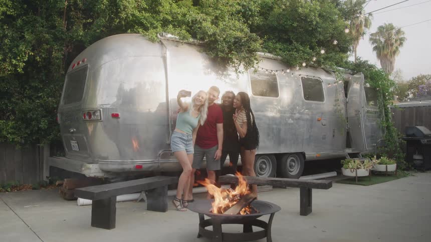 Friends taking a selfie in a backyard with a motorhome