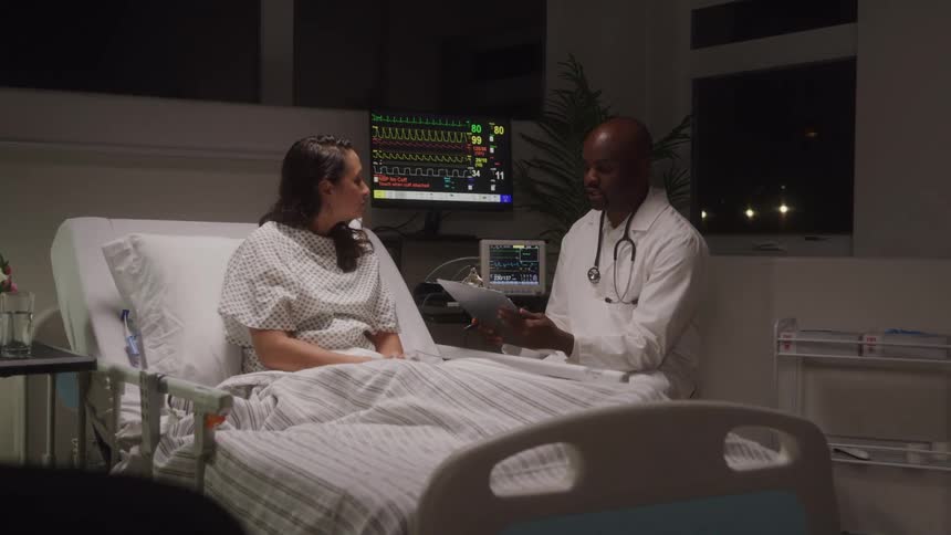 A doctor talks with a female patient in a hospital room