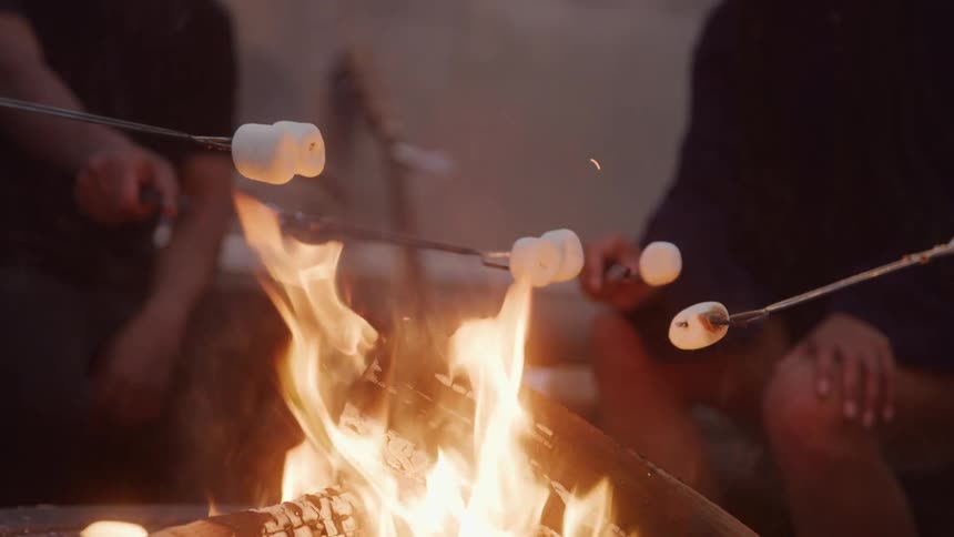 People toast marshmallows over a blazing fire during a cozy outdoor gathering