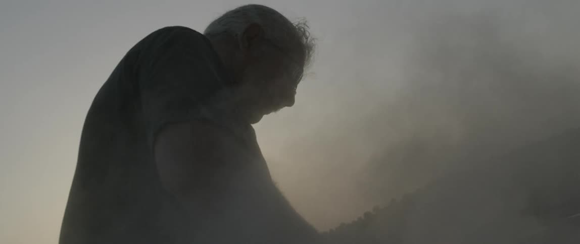 Dust blows around as a man sands something