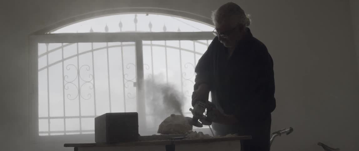 A man is using a sander on stone