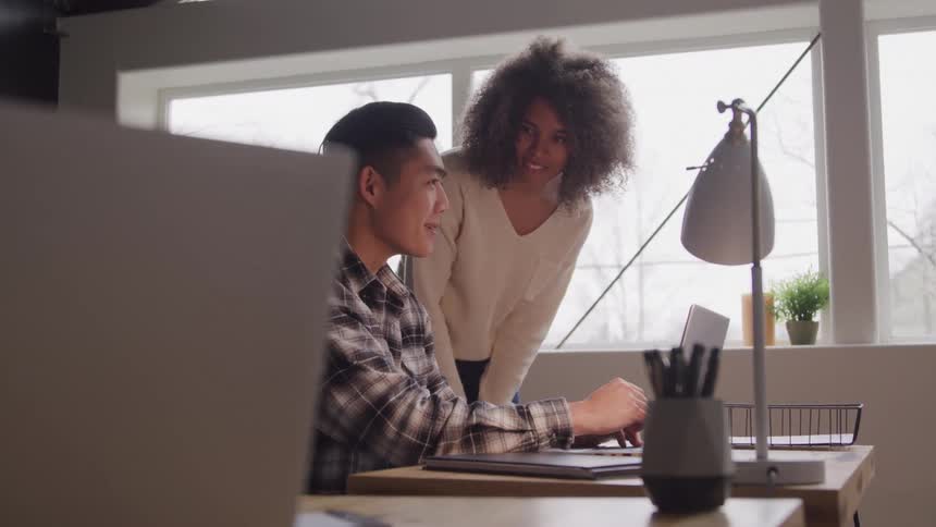 Two people in front of a laptop talking in an office