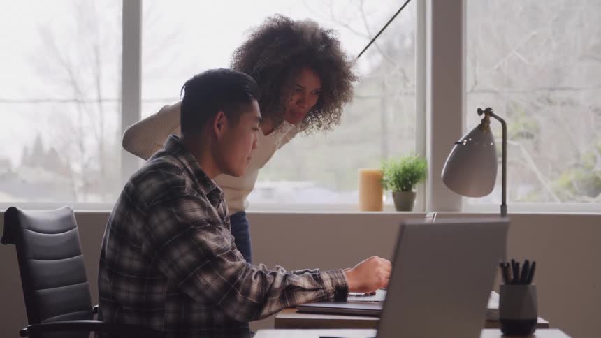 Two colleagues work together at a desk in a bright office