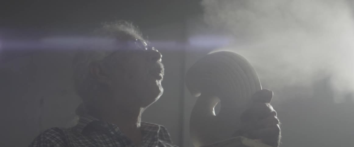 Man blowing dust off of a sculpture