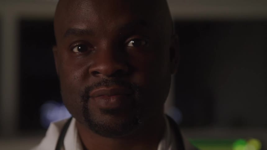 Closeup of a man with a neutral expression in dim light