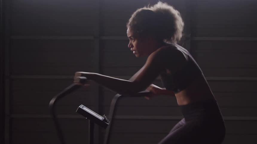 A woman is riding the exercise bike in the gym