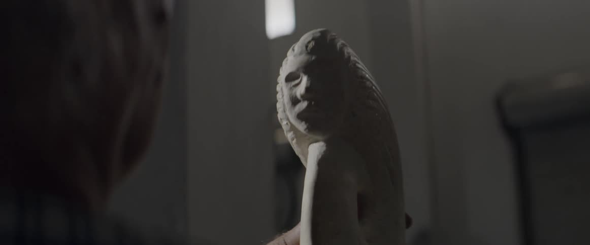 A person holds and looks at a stone sculpture