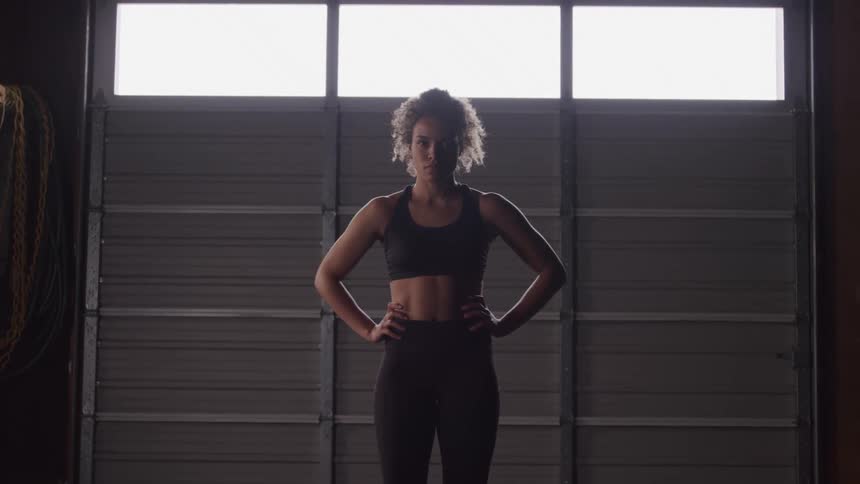 Woman with curly hair with her hand on her waist in an indoor space