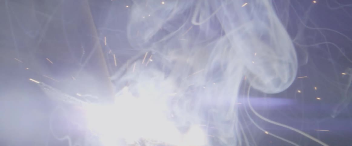 Sparks and smoke lift into the air as a man welds