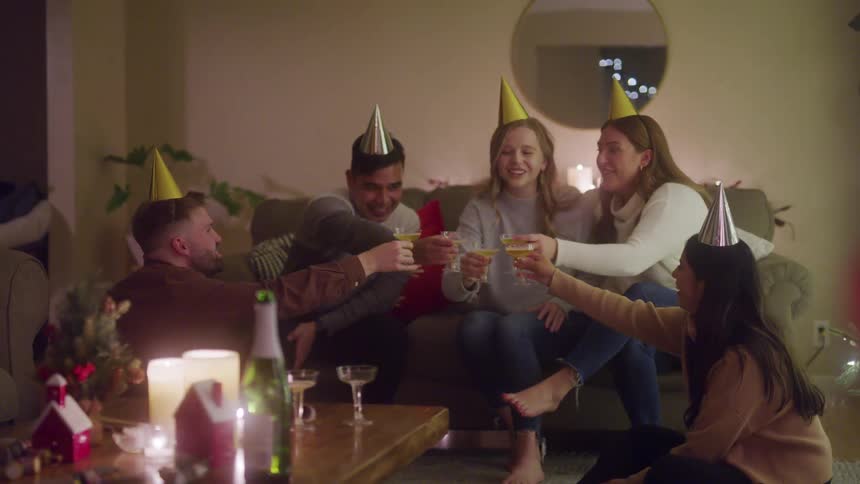 Friends wearing birthday hats toasting with champagne celebrating a birthday at home