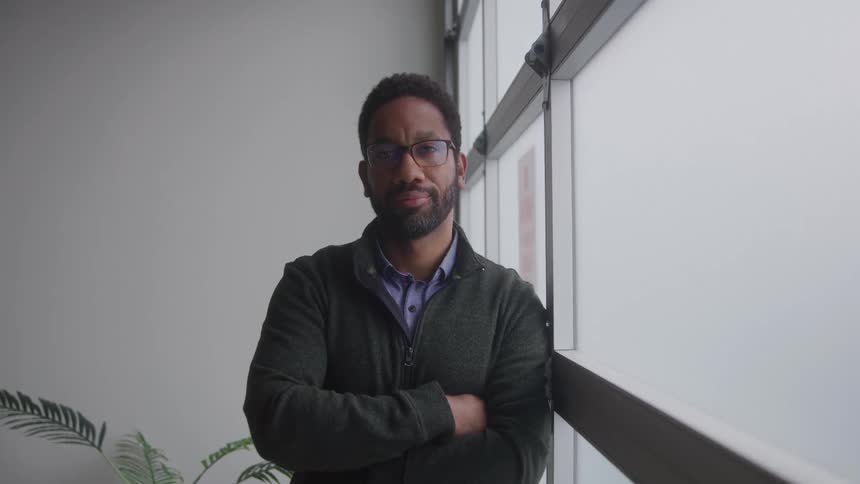Man with glasses with arms crossed in an office