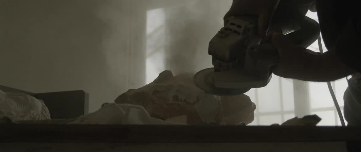 A sander is being used to form some stone