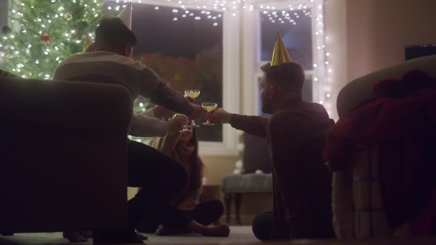 Friends wearing party hats toasting with champagne celebrating a birthday at home