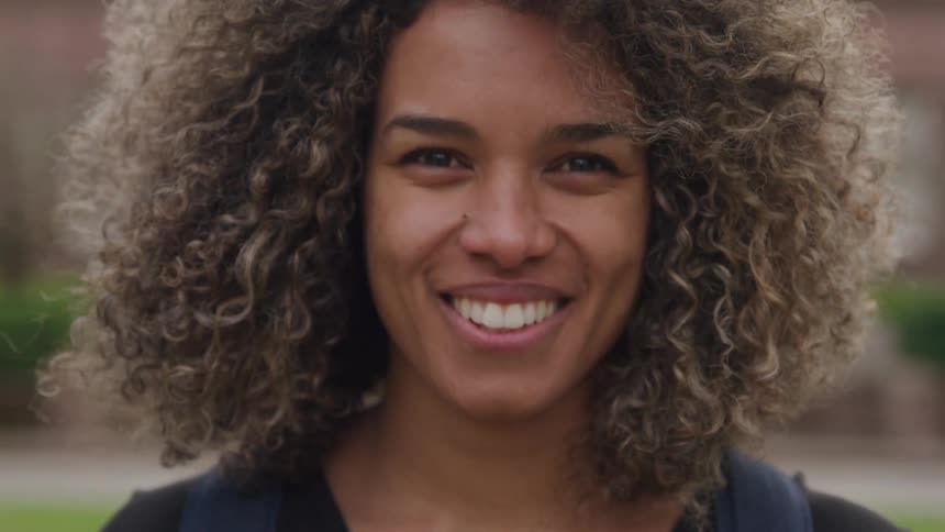 A womans head slowly turns towards the camera as she smiles