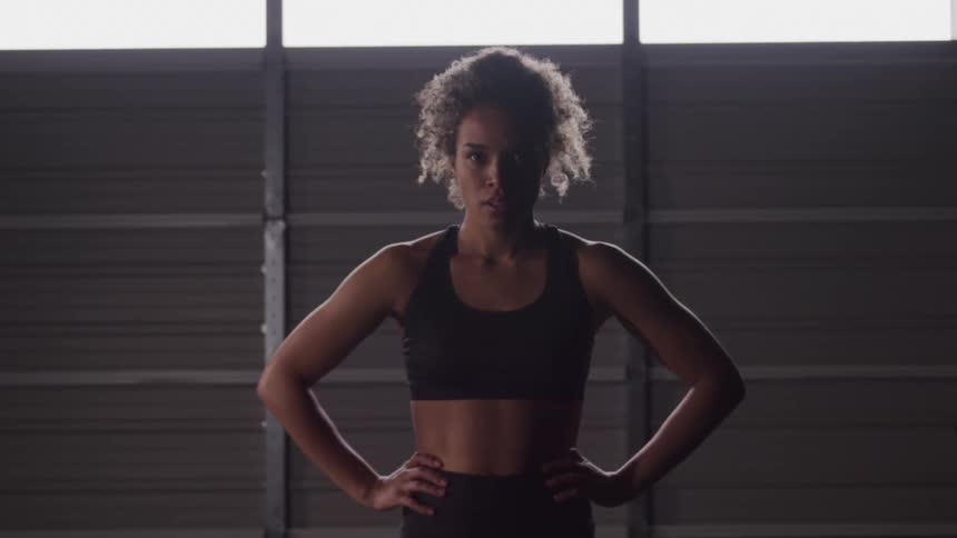 Fit woman stands confidently with hands on hips after workout