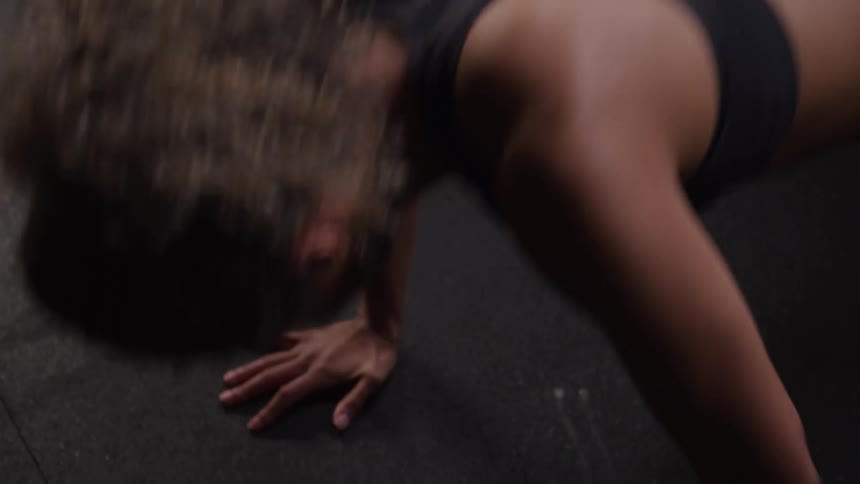 A woman wearing workout clothes does push ups on the ground