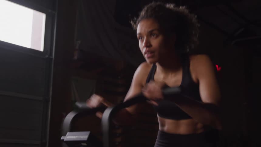 Woman exercises on a cardio machine with focus and determination