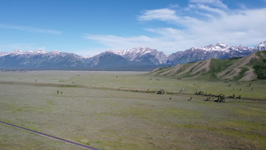 The long landscape is green with mountains on the edge