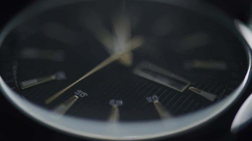 Closeup of a wristwatch with a moving golden hand