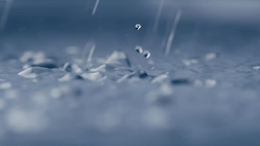 Close up of rain drops falling on water