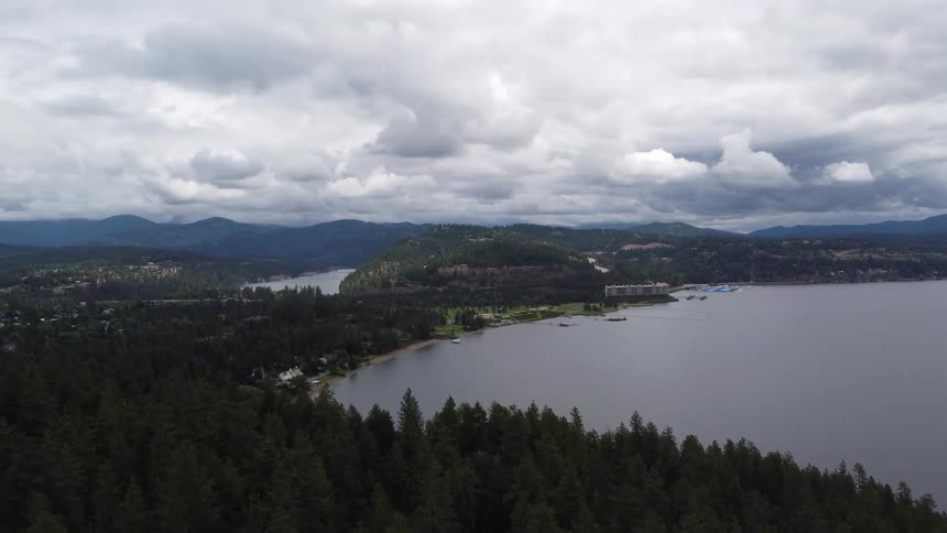 Aerial view of a lake with forests and mountains under clouds