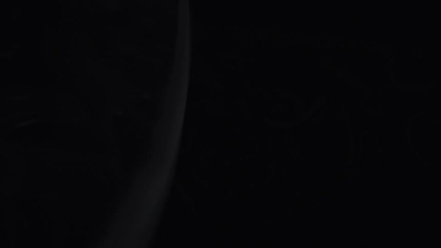 A close view shows light reflecting off a clear textured glass object with an organic pattern revealing a dark background with similar raised abstract designs