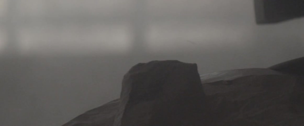 Dust sprays into the air as a person grinds a sculpture