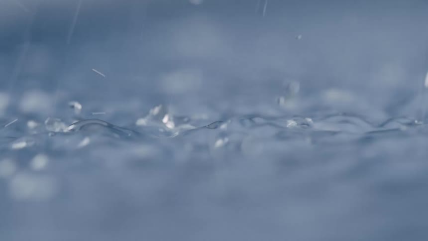 Close up of rain drops boucing on water during rain storm