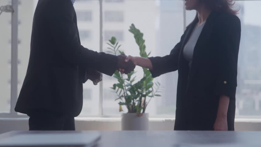 Two coworkers shake hands in the office
