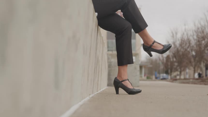 Close up of a woman crossing her legs as she uses her laptop while sitting outdoors during daytime