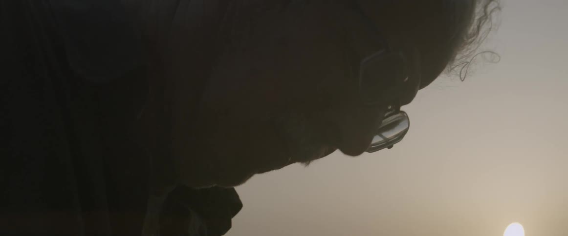 Dust flies around a man as the sun shines overhead