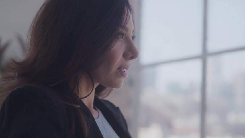 A woman is looking out the window in the office