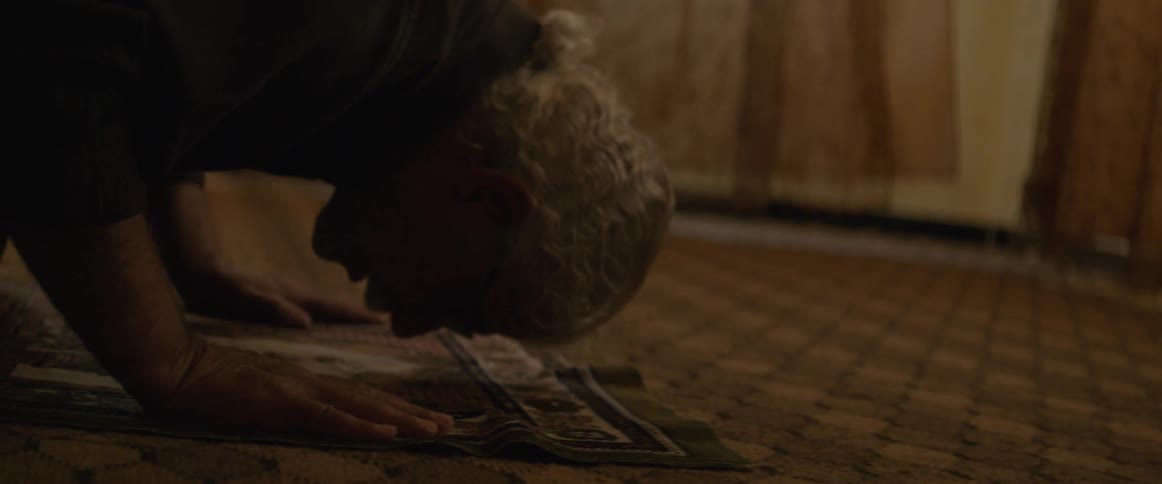 Man leaning down and bowing onto a carpet in a room