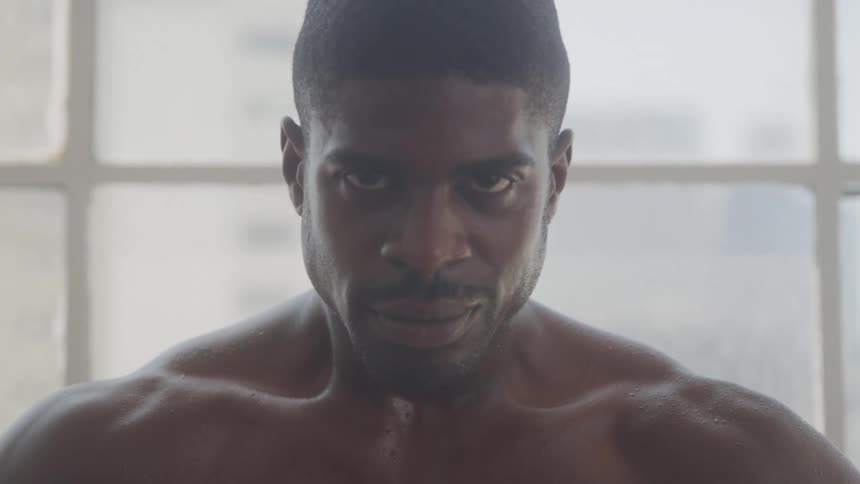 The video features a closeup of a muscular man with a dark complexion looking intensely at the camera he appears to be working out as evidenced by sweat glistening on his bare chest and shoulders