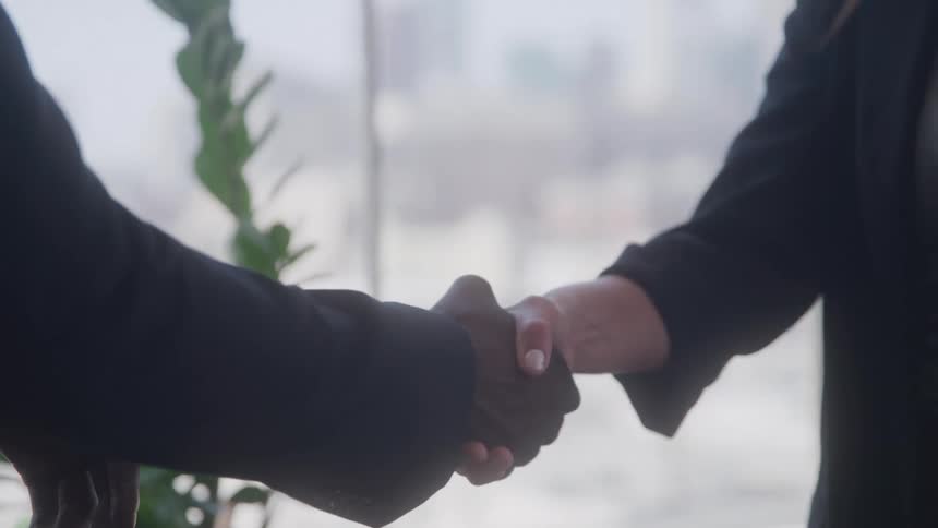 Close up of male and female coworkers shaking hands in an office during daytime