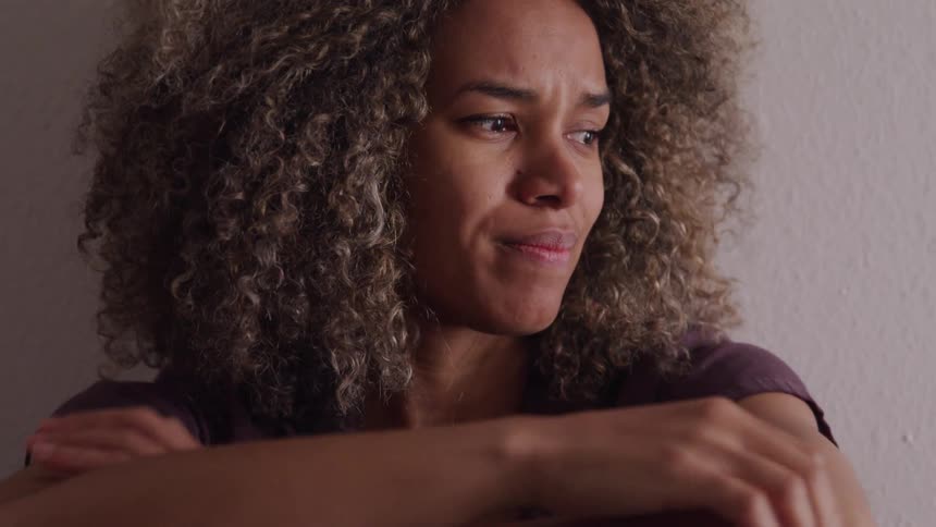 Woman with curly hair looking to the side with a strange expression
