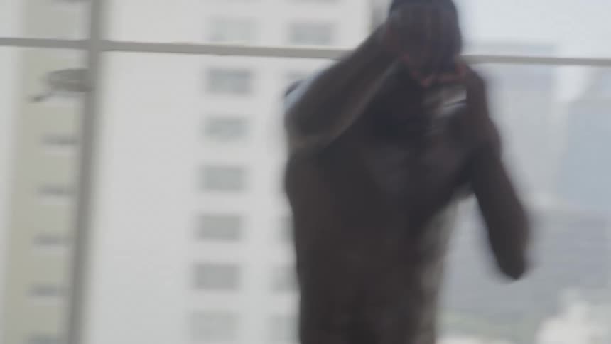 Male boxer shadow boxes near large windows showing a fog covered city