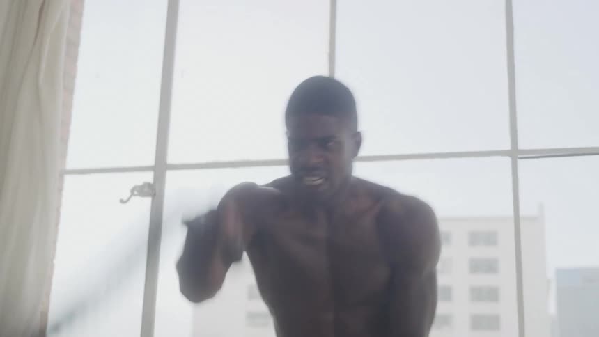A shirtless man works out with battle ropes indoors