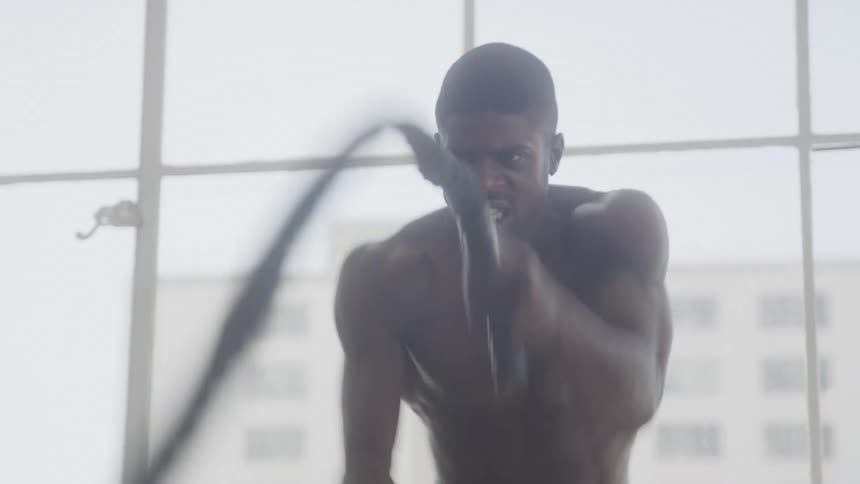 Male intensely doing a an arm and shoulder workout with ropes