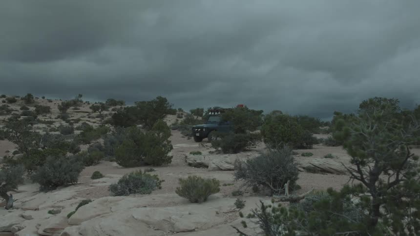 A jeep travels over rocks on a cloudy day
