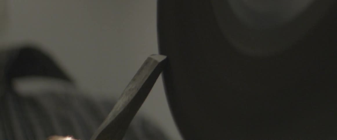 A sander is sharpening a chisel